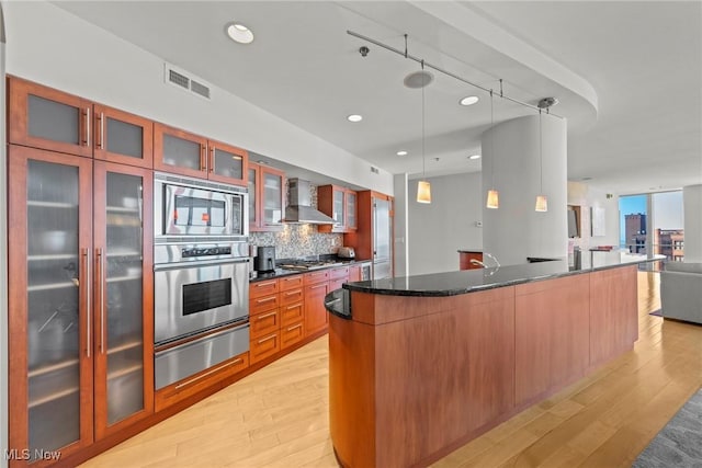 kitchen with a warming drawer, visible vents, open floor plan, stainless steel appliances, and wall chimney exhaust hood