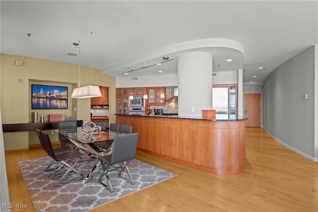 dining area featuring recessed lighting, baseboards, arched walkways, and light wood finished floors