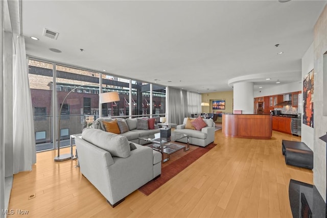 living room with floor to ceiling windows, light wood-style flooring, recessed lighting, and visible vents