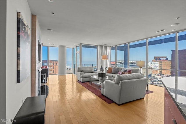 living area with a wall of windows, a view of city, light wood-style floors, and visible vents