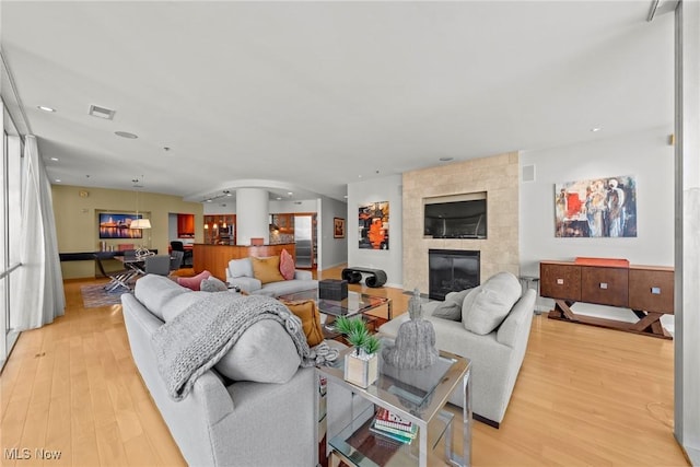 living room with recessed lighting, light wood-type flooring, visible vents, and a fireplace