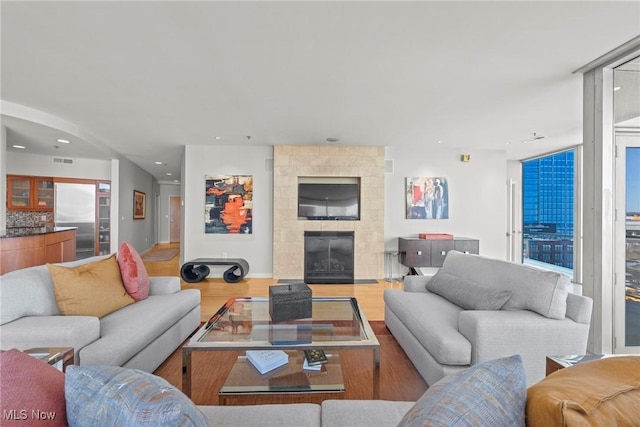 living area featuring recessed lighting, wood finished floors, visible vents, and a large fireplace