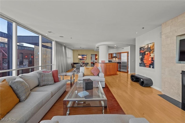 living room with visible vents, recessed lighting, light wood-style floors, a fireplace, and baseboards