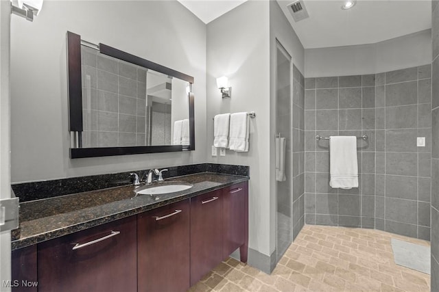 bathroom with vanity, visible vents, and a tile shower