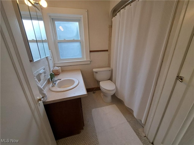 bathroom with toilet, vanity, and a shower with curtain