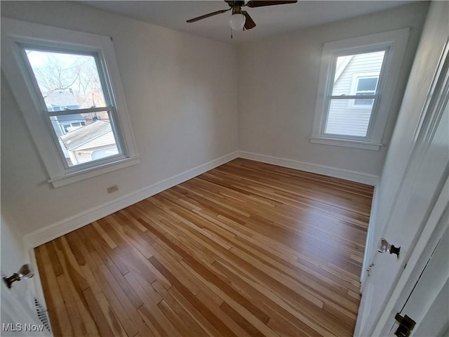 spare room featuring light wood-style flooring, baseboards, a healthy amount of sunlight, and a ceiling fan