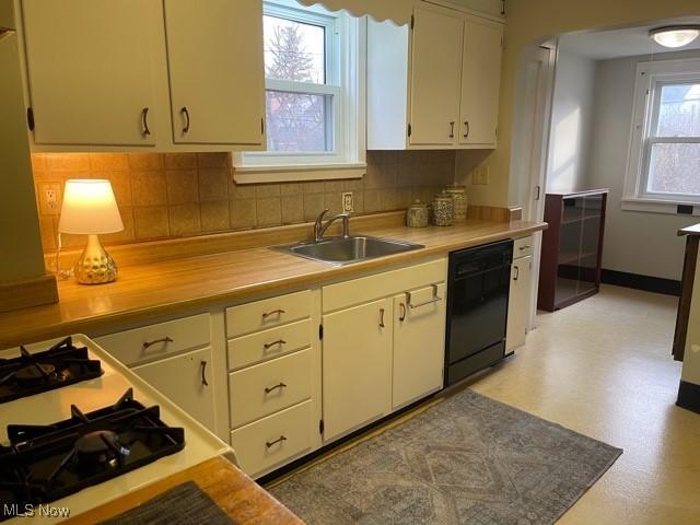 kitchen with a sink, decorative backsplash, light countertops, white cabinets, and dishwasher