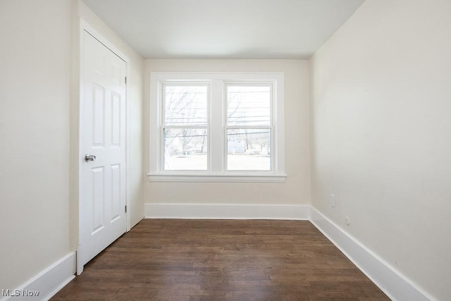 empty room featuring baseboards and dark wood finished floors