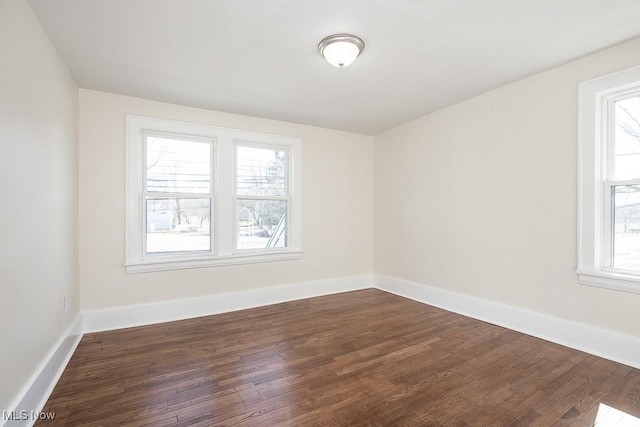 unfurnished room with dark wood-type flooring and baseboards