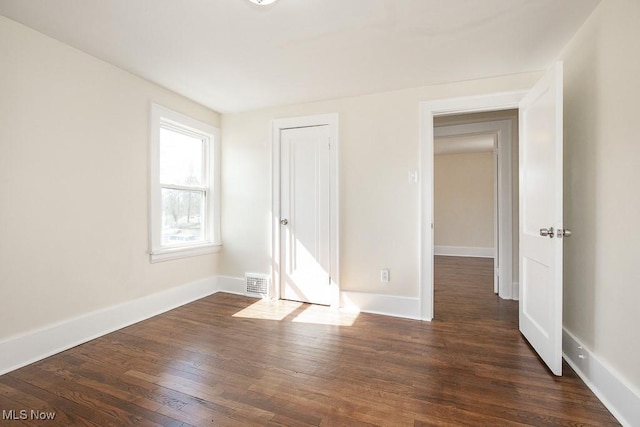 unfurnished bedroom featuring visible vents, dark wood-type flooring, and baseboards