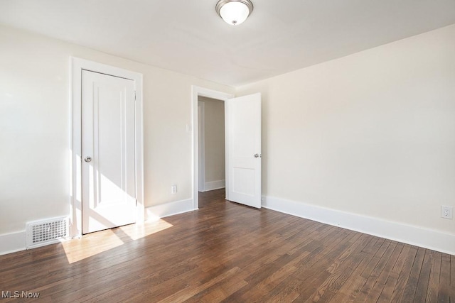 unfurnished room with dark wood finished floors, baseboards, and visible vents