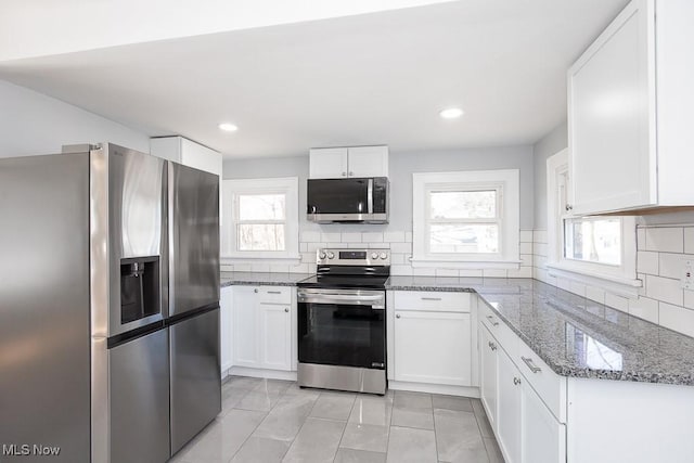 kitchen with white cabinets, backsplash, light stone countertops, and appliances with stainless steel finishes