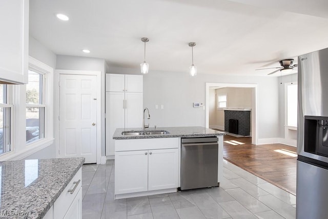 kitchen with a sink, stainless steel appliances, light stone countertops, and white cabinets