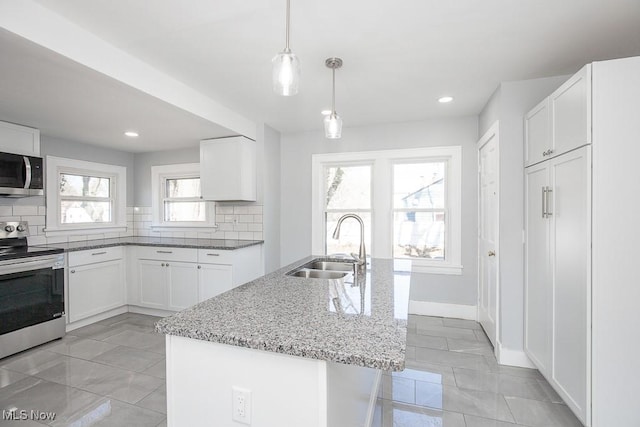 kitchen with a sink, light stone counters, appliances with stainless steel finishes, white cabinets, and decorative backsplash