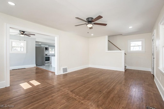 spare room featuring visible vents, wood finished floors, ceiling fan, and stairs