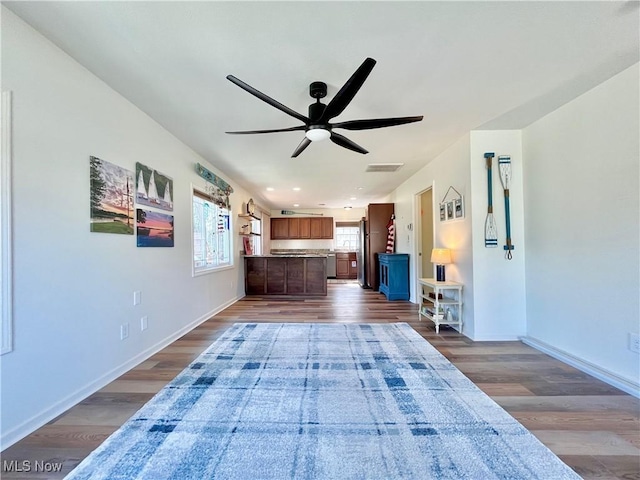 unfurnished living room featuring a ceiling fan, visible vents, wood finished floors, and baseboards