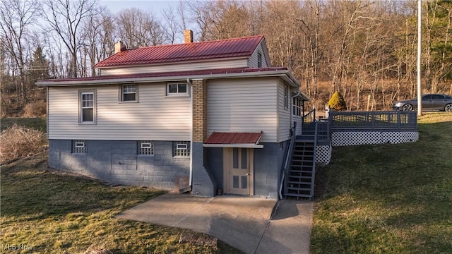 rear view of property featuring a lawn, a deck, stairway, a chimney, and a patio area