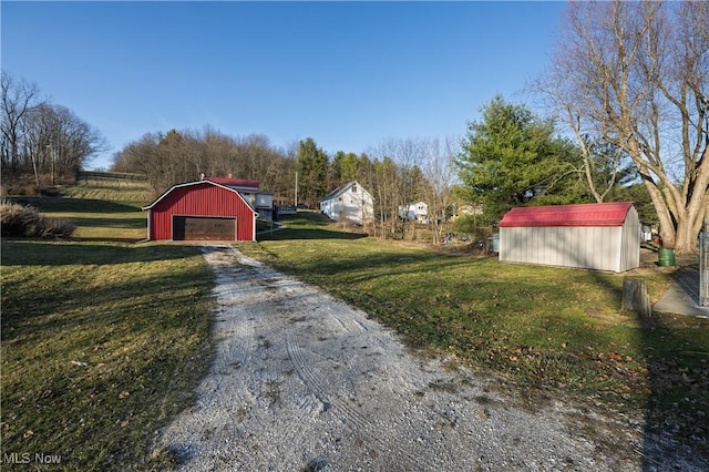 view of yard with an outbuilding, a detached garage, a barn, and dirt driveway