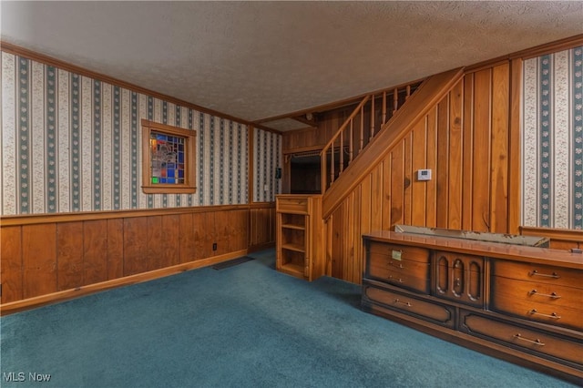 interior space with wallpapered walls, a textured ceiling, carpet, and wainscoting