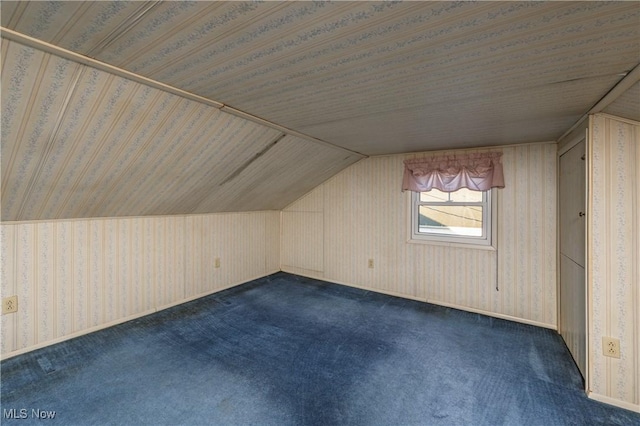 bonus room with lofted ceiling, dark carpet, and wallpapered walls