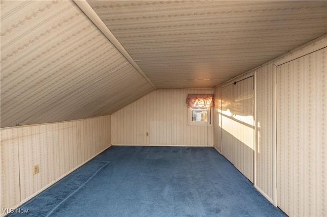 additional living space featuring dark colored carpet and vaulted ceiling