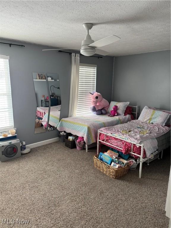 carpeted bedroom featuring baseboards, a textured ceiling, and ceiling fan