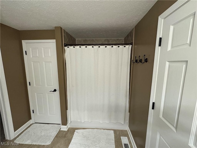 full bath with visible vents, curtained shower, a textured ceiling, and baseboards