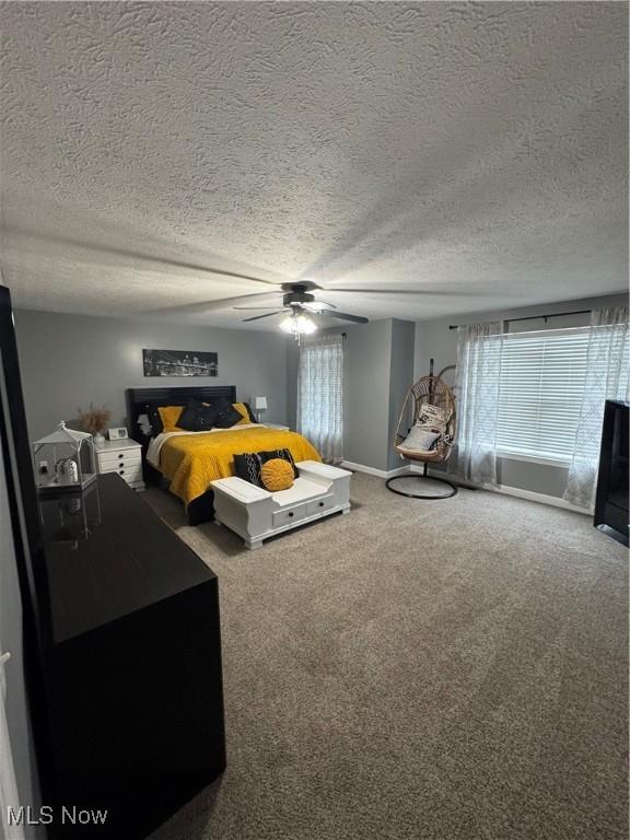 carpeted bedroom with a ceiling fan, baseboards, and a textured ceiling