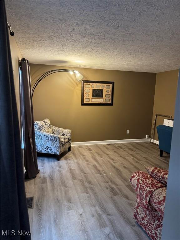 sitting room featuring wood finished floors, baseboards, and a textured ceiling