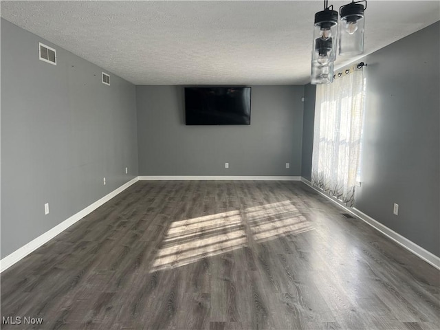 unfurnished room featuring baseboards, visible vents, dark wood-style flooring, and a textured ceiling