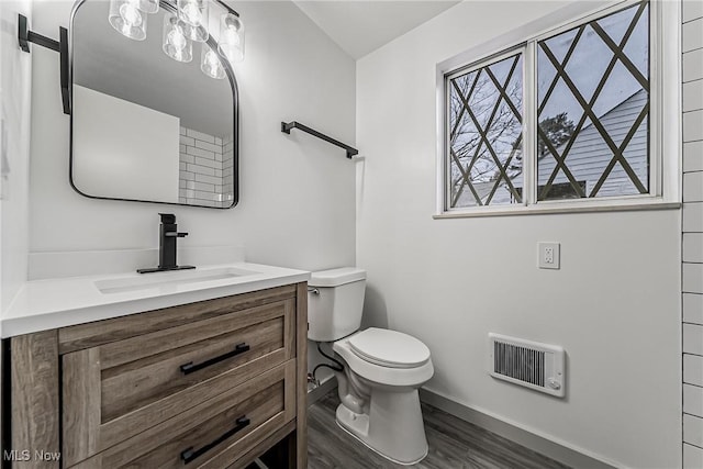 bathroom with vanity, wood finished floors, visible vents, baseboards, and toilet