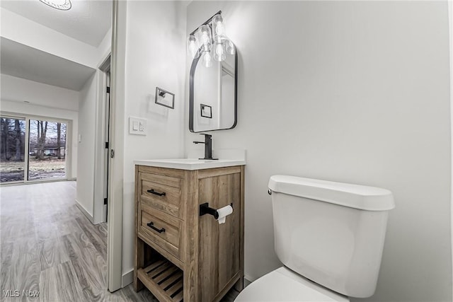 bathroom with toilet, vanity, baseboards, and wood finished floors