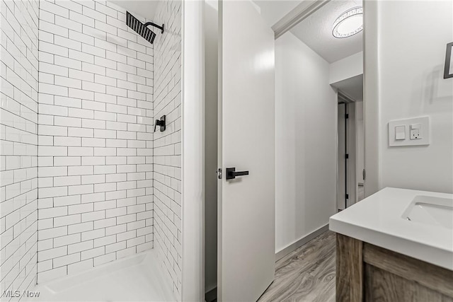 full bathroom featuring a sink, a shower stall, and wood finished floors