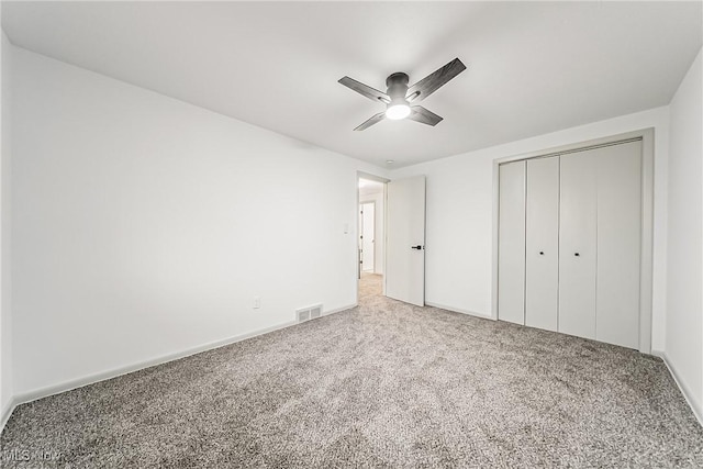 unfurnished bedroom featuring a ceiling fan, visible vents, carpet floors, baseboards, and a closet