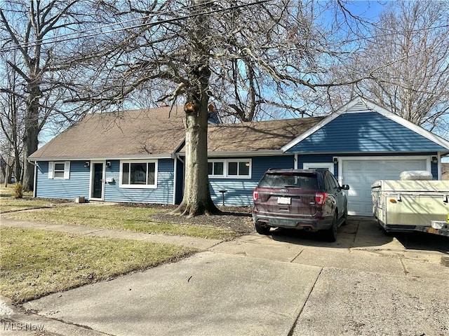 single story home with concrete driveway, an attached garage, a front yard, and a shingled roof