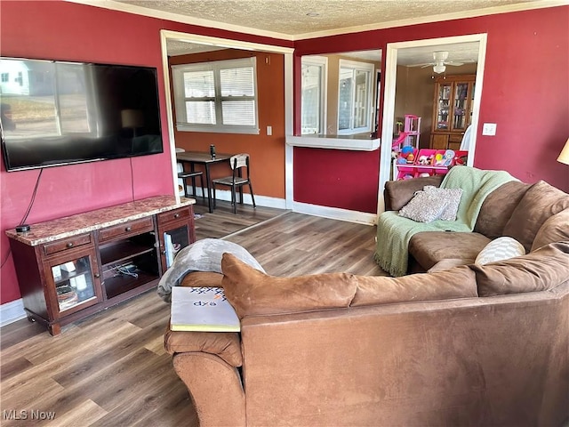 living area with baseboards, a textured ceiling, wood finished floors, and ornamental molding