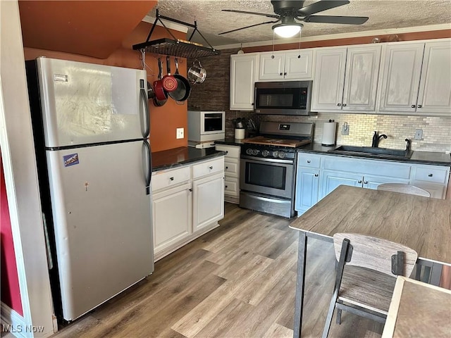 kitchen featuring dark countertops, appliances with stainless steel finishes, ceiling fan, and a sink