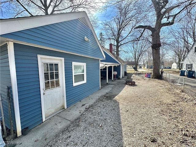 view of side of property featuring a chimney and fence