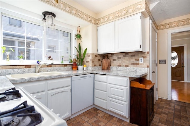 kitchen featuring white cabinetry, white dishwasher, a wealth of natural light, and a sink