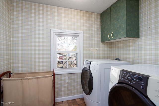 washroom with cabinet space, a textured ceiling, wallpapered walls, and separate washer and dryer