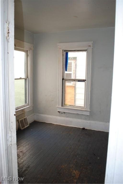 empty room with a wealth of natural light, baseboards, and hardwood / wood-style flooring