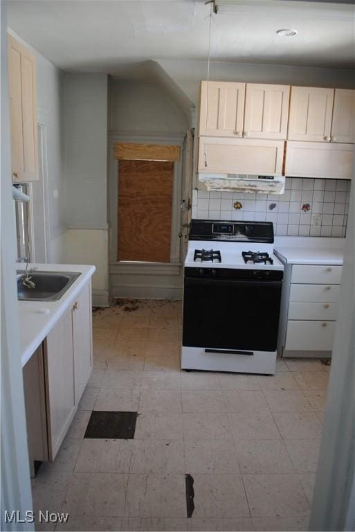 kitchen featuring decorative backsplash, gas stove, light countertops, and a sink