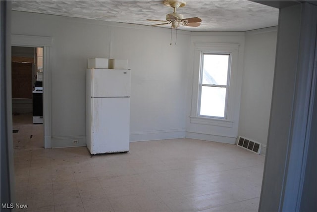 unfurnished room featuring a ceiling fan, baseboards, visible vents, light floors, and a textured ceiling