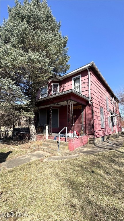 exterior space featuring covered porch and a front yard