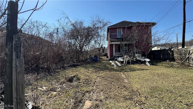 back of property with a lawn and fence