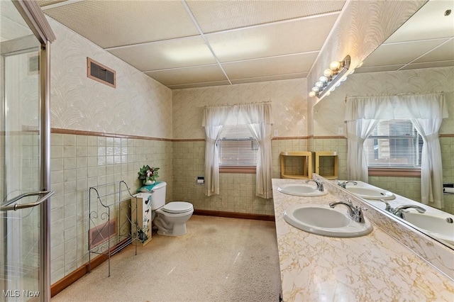 bathroom featuring a sink, a wainscoted wall, and wallpapered walls