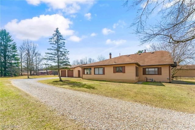 ranch-style house featuring a front lawn, gravel driveway, and a garage