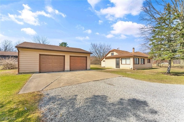 view of front of home with an outdoor structure, a front lawn, and a detached garage