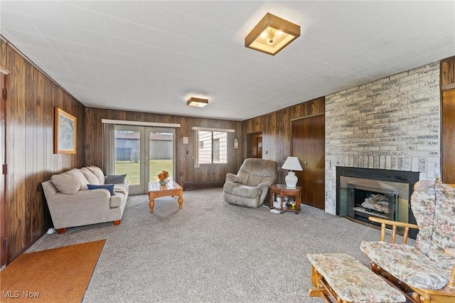 living area featuring carpet, a fireplace, and wood walls