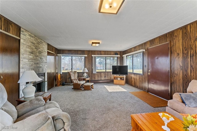 living room with baseboard heating, wood walls, a brick fireplace, and carpet flooring